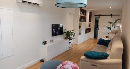 Salón reformado con muebles blancos a medida, suelo de madera y puerta corredera, trabajo de Carpintería Laura Egea