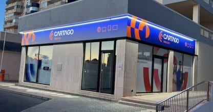 Fachada esquinera de Cartago Telecom con rótulo azul y naranja iluminado, La Manga del Mar Menor