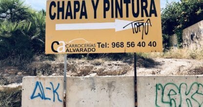 Cartel amarillo de Carrocerías Alvarado indicando servicio de chapa y pintura con teléfono de contacto en La Manga del Mar Menor
