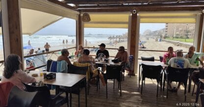 Terraza del Chiringuito 4 Latas con clientes almorzando frente a la playa y el mar agitado en La Manga del Mar Menor