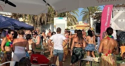 Fiesta en la playa del Chiringuito de Lola con gente bailando bajo sombrillas Budweiser y ambiente tropical en La Manga del Mar Menor