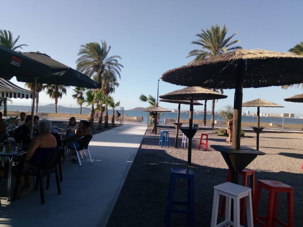 Terraza frente al Mar Menor con sombrillas de paja y clientes en el Chiringuito El Rincón Cubano