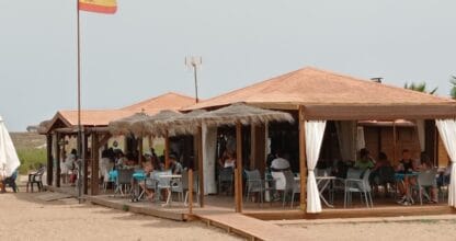 Terraza exterior del Chiringuito Punta de Lomas con mesas llenas de clientes bajo techos de palma y cortinas blancas en La Manga del Mar Menor
