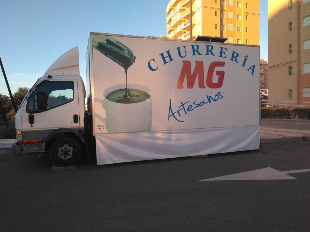 Furgón rotulado de Churrería MG Artesanos con imagen de chocolate caliente aparcado en La Manga del Mar Menor