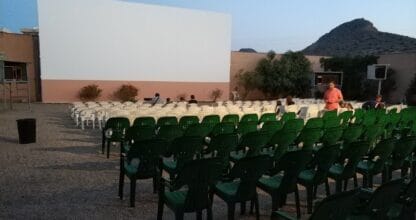 Cine de verano al aire libre en Cabo de Palos con sillas verdes y blancas frente a gran pantalla al atardecer con montaña al fondo