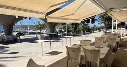 Terraza del Club Náutico Dos Mares con mesas blancas y vistas al puerto deportivo con veleros amarrados en La Manga del Mar Menor