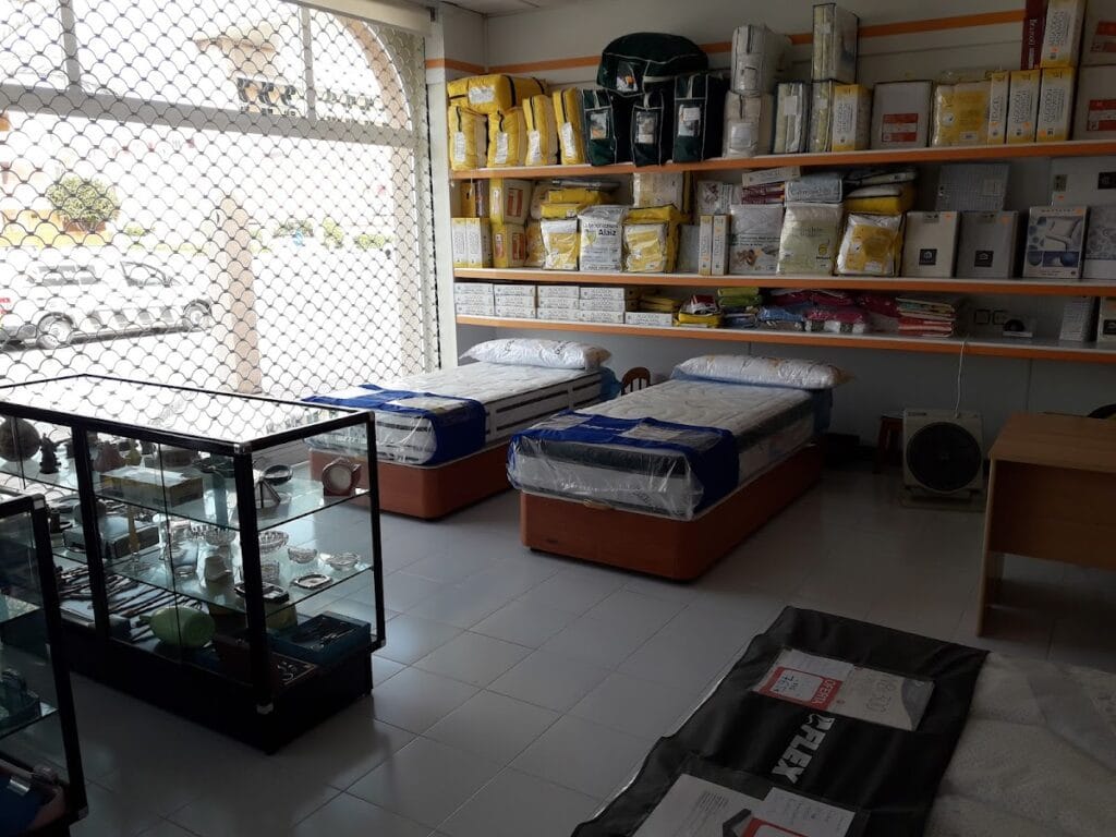 Interior de Establecimientos Angosto con colchones expuestos en bases tapizadas y estantes con textiles