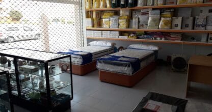 Interior de Establecimientos Angosto con colchones expuestos en bases tapizadas y estantes con textiles