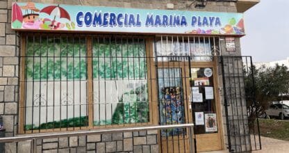 Fachada exterior de Comercial Marina Playa con letrero colorido y rejas en escaparate, La Manga del Mar Menor