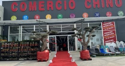 Fachada del Comercio Chino La Manga con alfombra roja de inauguración, árboles decorativos y plantas a la entrada