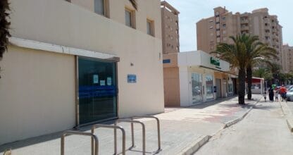 Fachada del Consultorio de la plaza del Cavanna con puerta acristalada azul y aparcabicicletas en La Manga del Mar Menor