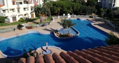 Vista aérea de piscina comunitaria con palmeras y jardines en urbanización residencial de Cabo de Palos