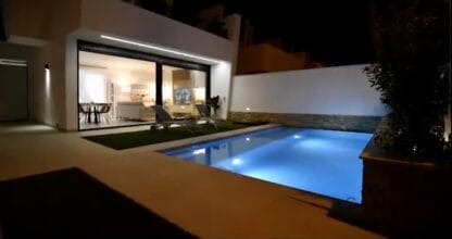 Villa moderna de COSTA SPAIN Real Estate con piscina privada iluminada de noche y salón acristalado en La Manga del Mar Menor