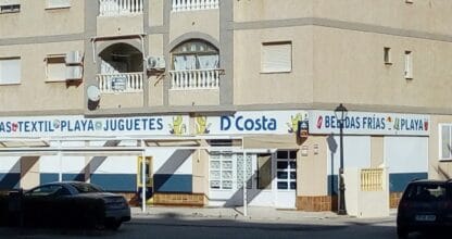 Fachada de D'Costa con rótulos de textil, juguetes y bebidas frías para la playa, La Manga del Mar Menor