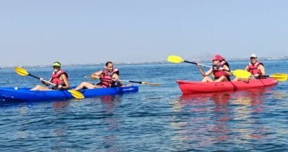 Cuatro personas en kayaks azul y rojo con chalecos salvavidas en las aguas del Mar Menor, David's Sailing School
