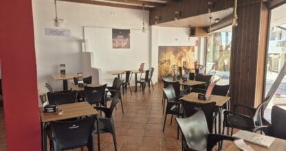 Sala interior de Di Giorgio Pizzería en La Manga del Mar Menor con sillas negras, techo de madera oscura y decoración italiana