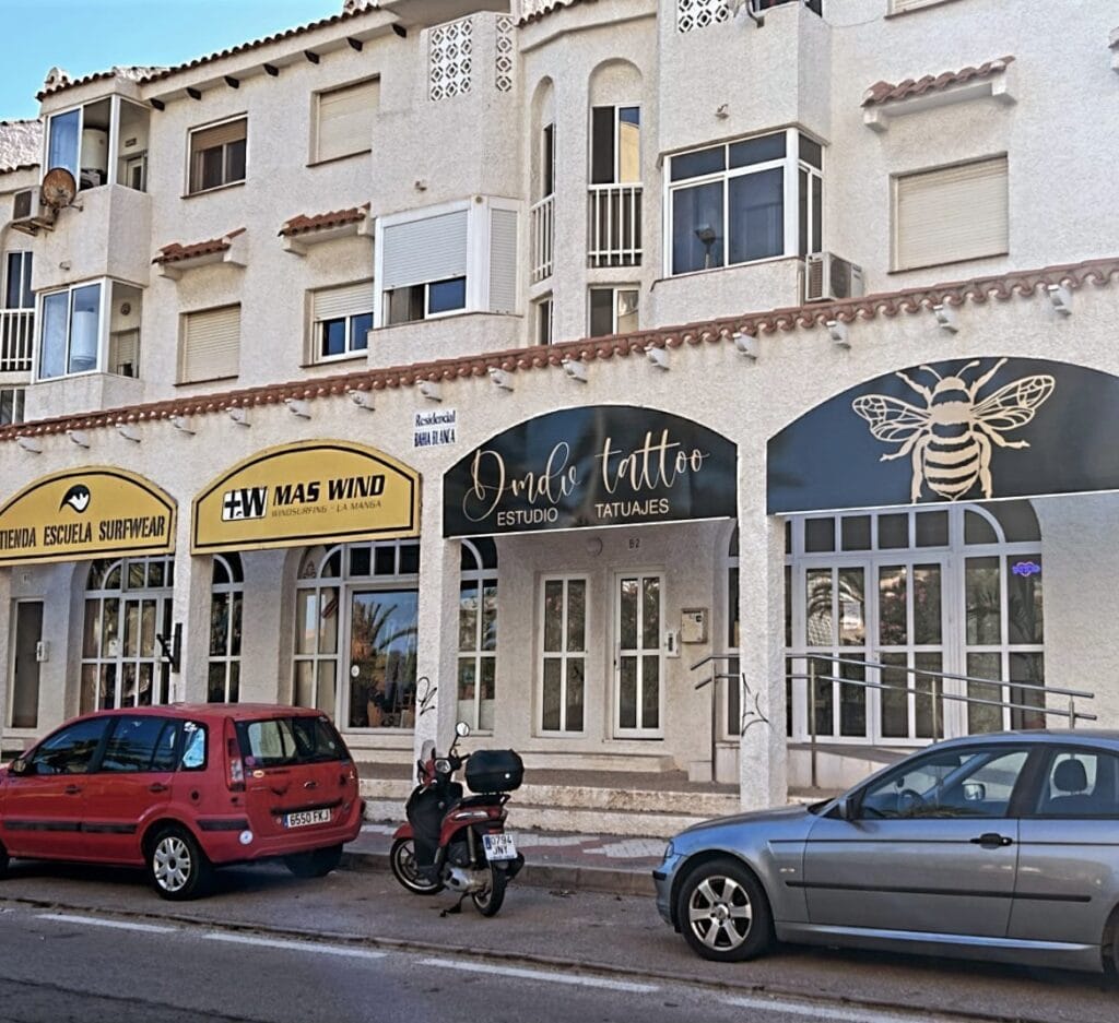 Fachada de Dmdv Tattoo estudio de tatuajes con rótulo negro y dibujo de abeja dorada en La Manga del Mar Menor