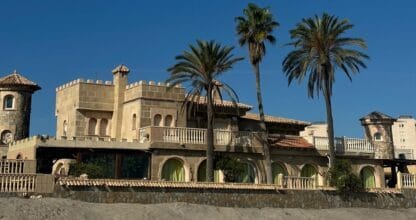 Edificio El Castillo de La Manga con arquitectura de castillo medieval, torretas y palmeras frente a la playa
