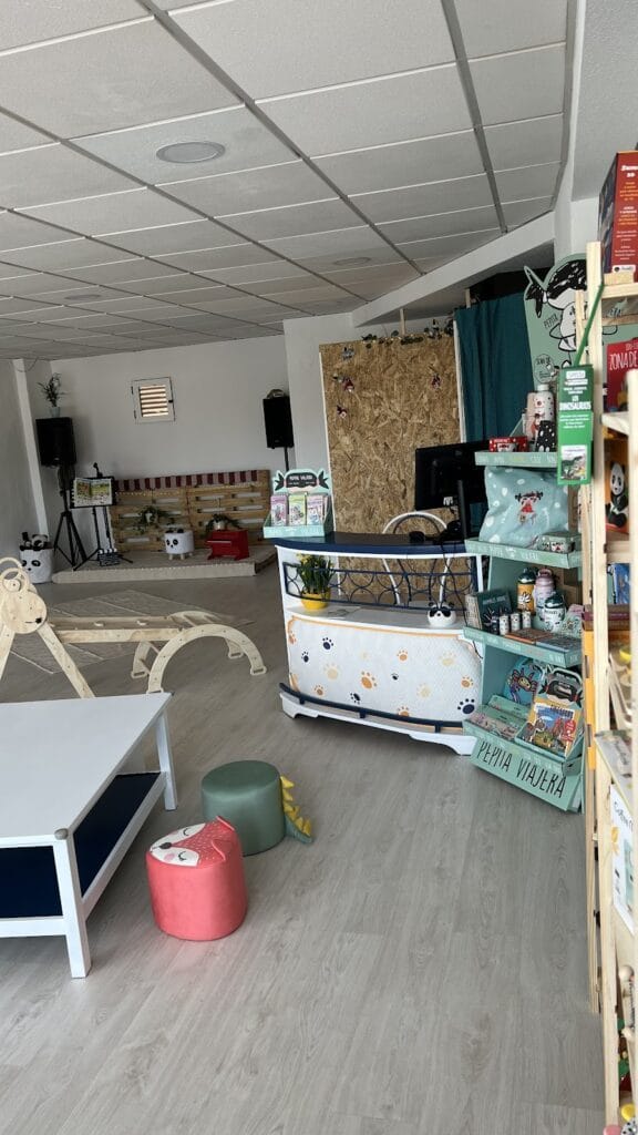 Interior de El Circo de Hugo con mostrador decorado, estantería de juguetes y libros y zona de juego infantil
