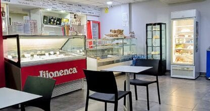 Interior de El Pedregal Heladería Cafetería con mostrador Jijonenca, vitrinas de helados artesanos y mesas con sillas negras