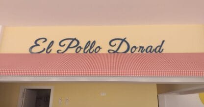 Interior de El Pollo Dorado La Manga con mostrador de servicio y rótulo retro amarillo con cuadros rojos y blancos
