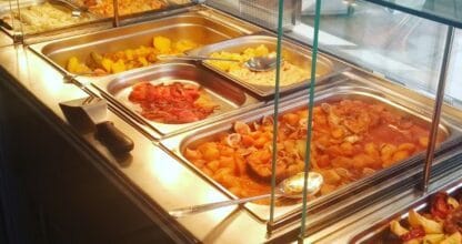 Mostrador de buffet de El Pollo Dorado La Manga con bandejas de guisos, mariscos, patatas y platos caseros calientes