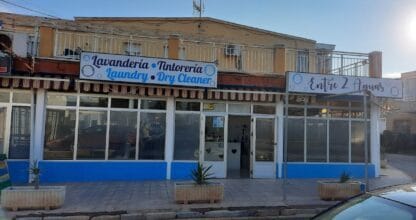 Fachada de lavandería y tintorería Entre 2 Aguas con rótulo bilingüe español e inglés, local de servicios en La Manga del Mar Menor