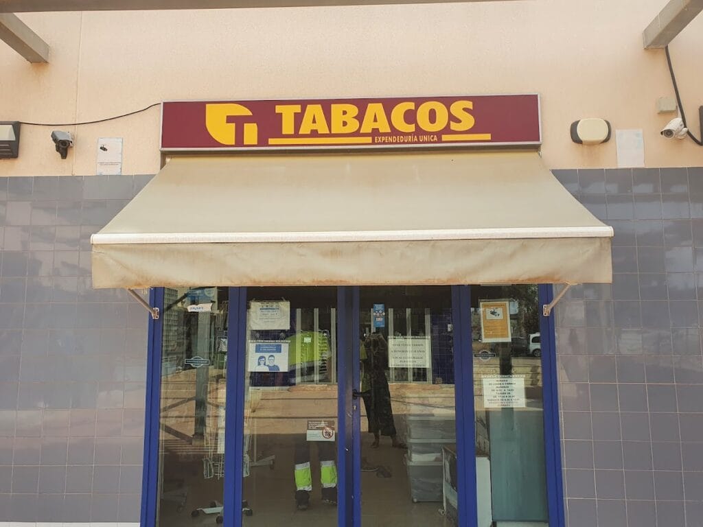 Estanco expendeduría única de Cabo de Palos con cartel rojo y amarillo de Tabacos, toldo crema y fachada de azulejo azul