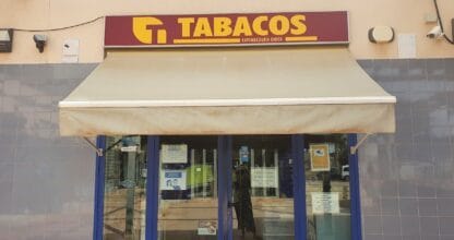 Estanco expendeduría única de Cabo de Palos con cartel rojo y amarillo de Tabacos, toldo crema y fachada de azulejo azul