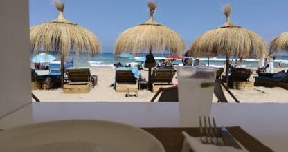 Vista desde la mesa de Fanático Beach hacia la playa con hamacas, sombrillas de paja y mar azul en La Manga del Mar Menor