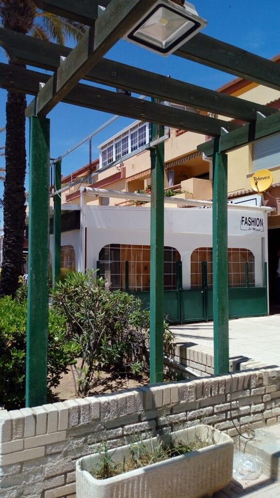Exterior de Fashion La Manga visto desde pérgola con vegetación y cielo azul en La Manga del Mar Menor