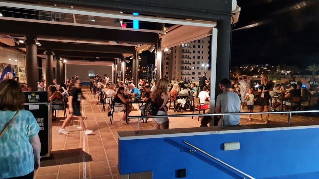 Terraza nocturna de Foster's Hollywood en La Manga llena de comensales bajo techo retráctil con vistas a edificios iluminados
