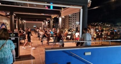 Terraza nocturna de Foster's Hollywood en La Manga llena de comensales bajo techo retráctil con vistas a edificios iluminados