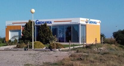 Edificio moderno blanco y amarillo de Grimanga con grandes ventanales, rodeado de vegetación en La Manga del Mar Menor