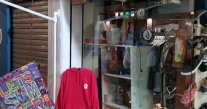 Entrada de Hookipa Surf Shop con ropa de surf, chanclas y tabla de madera como rótulo en La Manga del Mar Menor