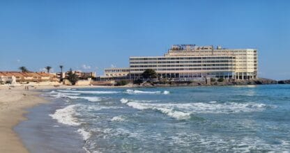 Hotel Servigroup Galúa visto desde la orilla de la playa con el mar Mediterráneo en primer plano en La Manga del Mar Menor