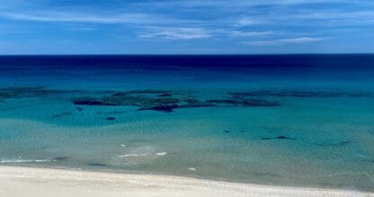 Playa de arena blanca con aguas turquesas cristalinas y fondos de posidonia visibles, zona costera de La Manga del Mar Menor