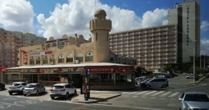Edificio comercial con torre característica donde se ubica Independent Consultants SL en La Manga del Mar Menor, con Hotel Cavanna al fondo