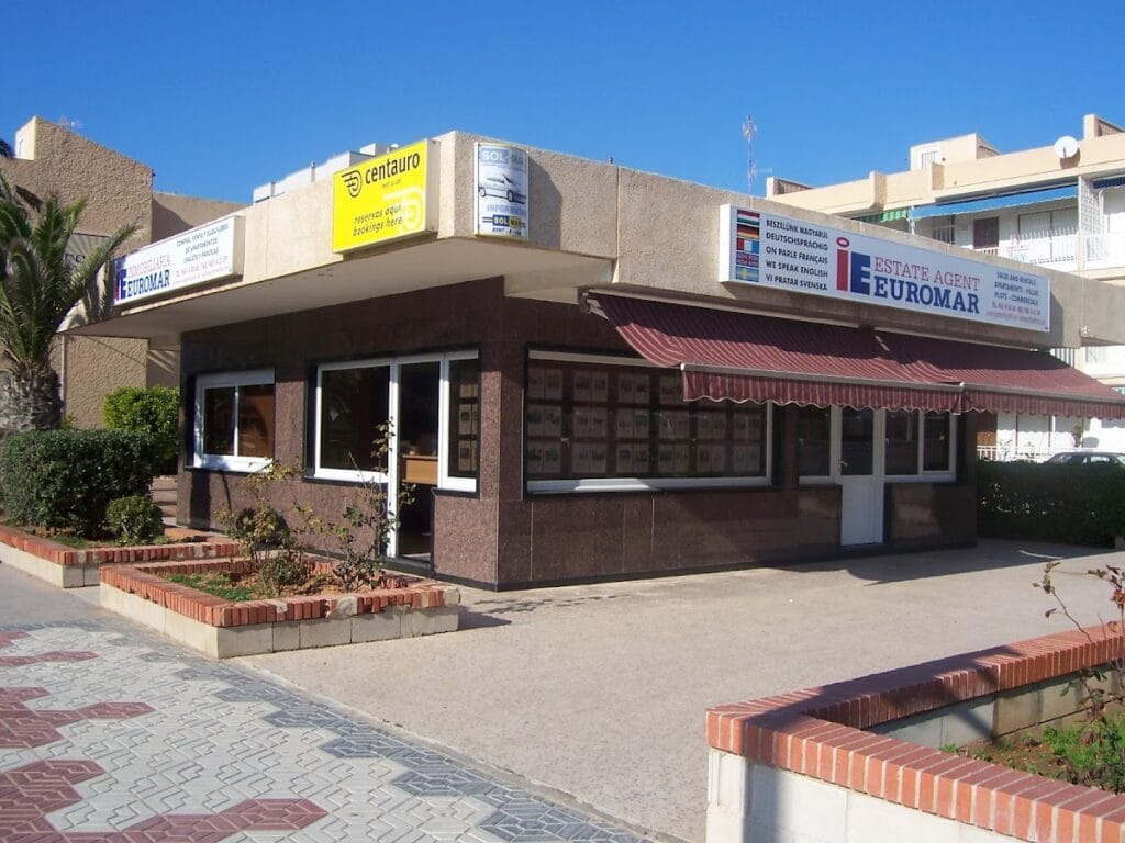 Oficina de Inmobiliaria Euromar en La Manga del Mar Menor, local de planta baja con escaparate de propiedades y toldo a rayas