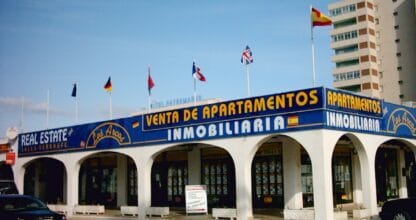 Fachada de Inmobiliaria Los Arcos en La Manga del Mar Menor con arcos blancos, rótulo azul y banderas internacionales