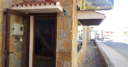 Fachada de piedra con cartel de Reformas y Servicios Inmobiliarios de Manmenor Mar Menor en La Manga del Mar Menor