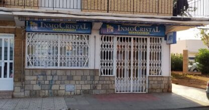 Oficina inmobiliaria InmoCristal Properties con fachada de piedra, rejas blancas y rótulos azules, La Manga