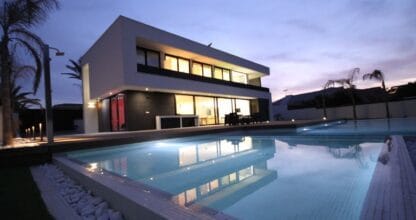 Villa Gawy de Inmovecos, villa moderna de dos plantas con gran piscina privada iluminada al atardecer y palmeras