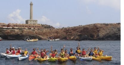 Grupo de kayakistas con chalecos salvavidas frente al faro de Cabo de Palos con Kayak Cabo de Palos DACAR