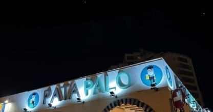 Fachada nocturna iluminada de restaurante Ke rico nico con letrero azul luminoso y arcos decorativos en La Manga del Mar Menor