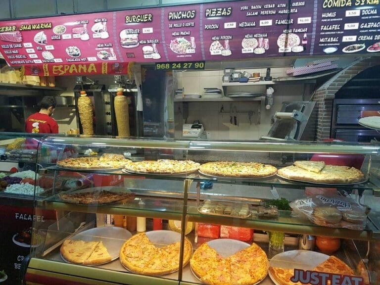 Interior de King Kebab en La Manga del Mar Menor con mostrador de pizzas y espetos de shawarma con carta en árabe y español