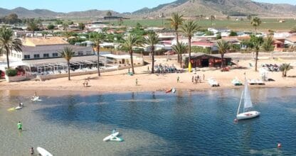 Vista aérea de playa del Mar Menor con velero, tablas de paddle surf y alumnos de KSURF La Manga en la orilla