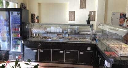 Mostrador buffet con vitrina de platos calientes, nevera de bebidas y vitrinas de bocadillos en La Boutique Del Buen Comer