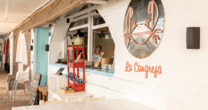 Fachada blanca del restaurante La Cangreja en Cabo de Palos con logotipo de cangrejo y barra de madera pintada al estilo marinero