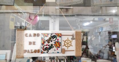 Escaparate de La Isa con tabla decorativa de madera con la leyenda Cabo de Palos, lagartija multicolor, timón marino y detalles náuticos